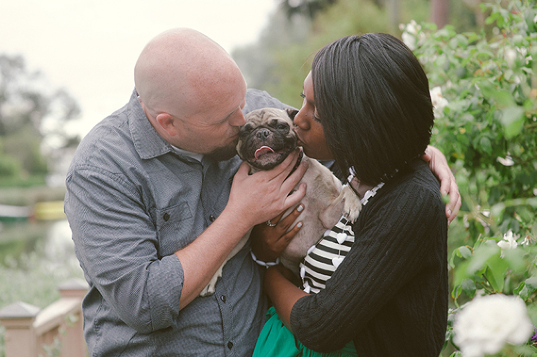 mixed cupel kissing their pug dog