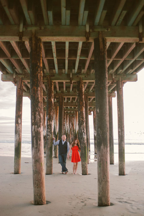 Filipino couple holding hands under wooden pier at Seal Beach California