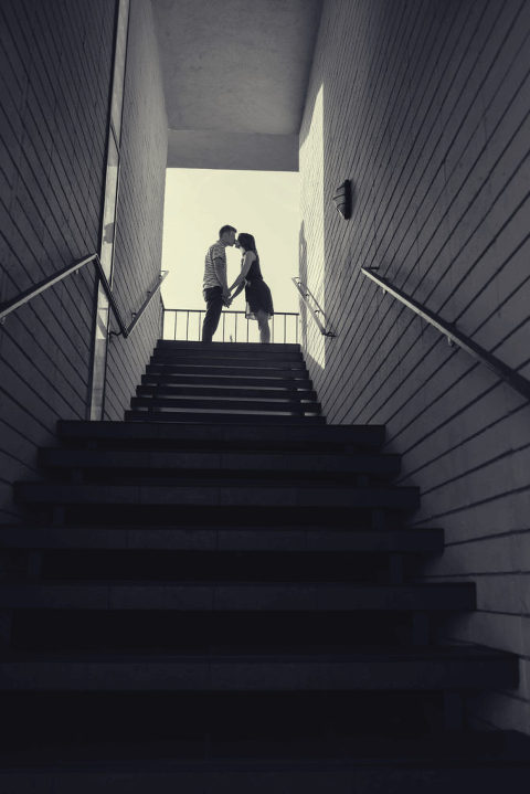 black and white silhouette of couple kissing at top of stairs