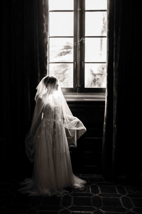 bride with veil on her head next to window in mural room of santa barbara courthouse