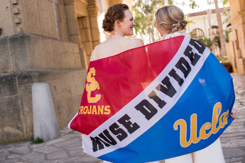 two brides with their UCLA and USC flag at the Santa Barbara courthouse Mural Room