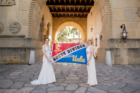 two brides with their UCLA and USC flag at the Santa Barbara courthouse Mural Room