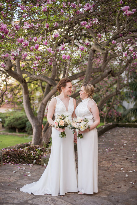 two brides in front of pink tree at their Santa Barbara courthouse wedding
