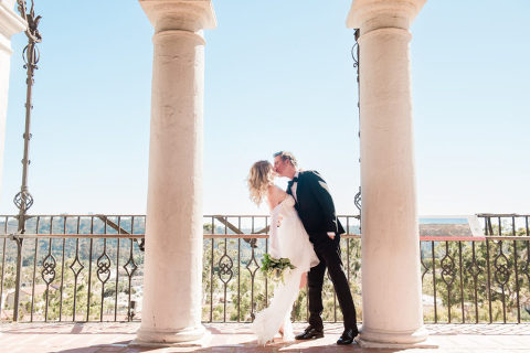 Caucasian bride and groom kissing the Santa Barbara Courthouse