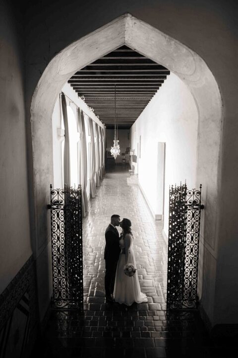bride and groom kissing under archway of santa barbara courthouse