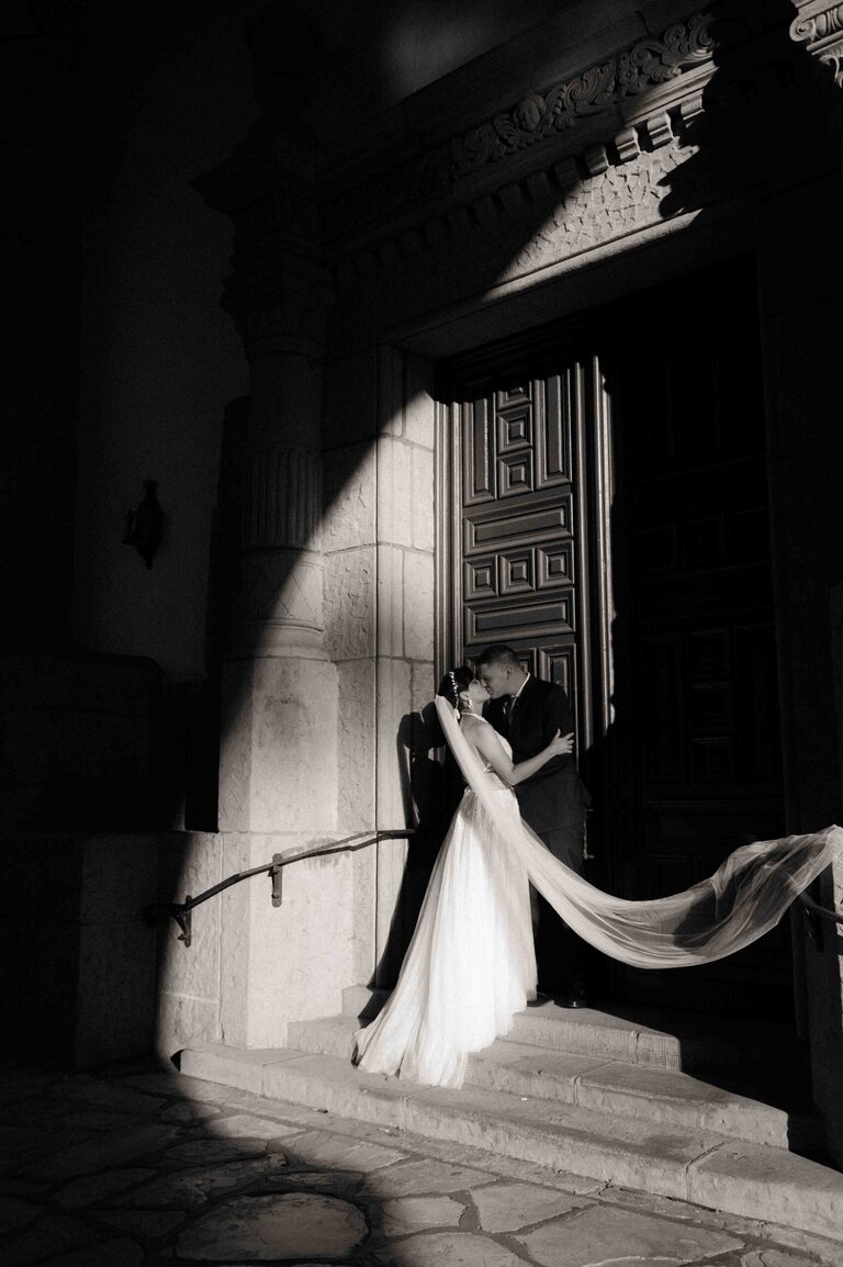 bride and groom kissing in front of decorative door