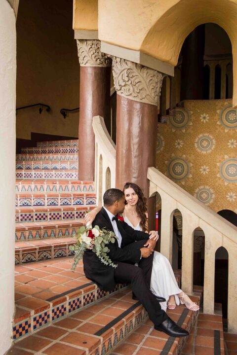 bride and groom sitting on stairs of circular staircase at santa barbara courthouse