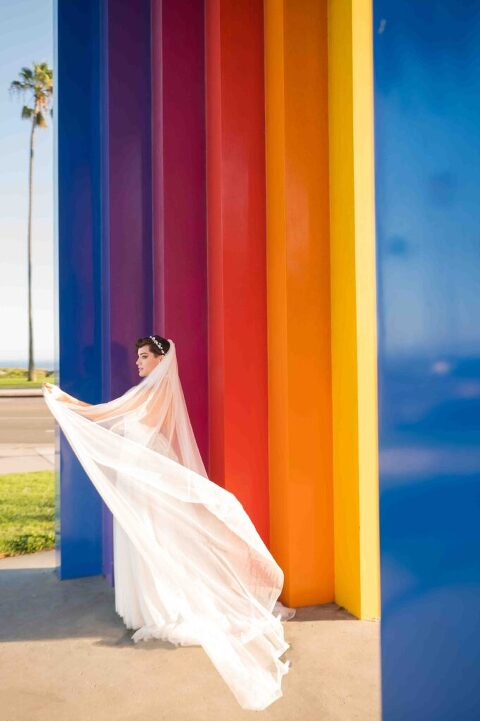 bride playing with her long veil next to Chromatic Gate in santa barbara at east beach