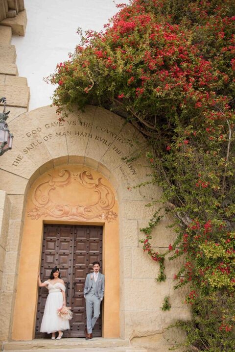 Bride and groom smiling at entrance of the Santa Barbara Courthouse under a doorway arch