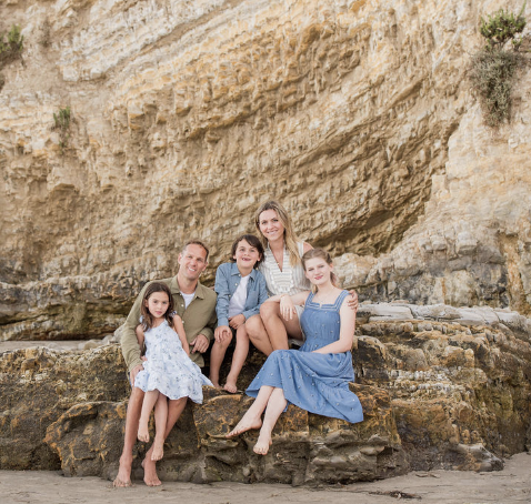 family of 5 sitting on rock at Ledbetter Beach in Santa Barbara
